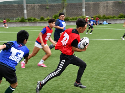 特徴
T-1ラグビーは激しい身体的な接触をなくしたラグビーの新しい形です。タックルの代わりにタッチで攻撃を阻止します。スクラムやラインアウトといったセットプレーがありながら、ボールの争奪をなくすことによって危険性を取り除いています。身体接触を避けながら、コンタクトラグビーの特徴的なプレーをすることができます。競技規則はありますが、状況に応じてフレキシブルにルールを変更して楽しむことができます。
対象
T-1ラグビーはラグビー経験者だけでなく未経験者でも始めやすいのが特徴です。年齢・性別を超えて楽しむことができるラグビーです。